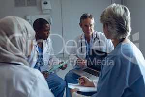 Medical team discussing over laptop in hospital