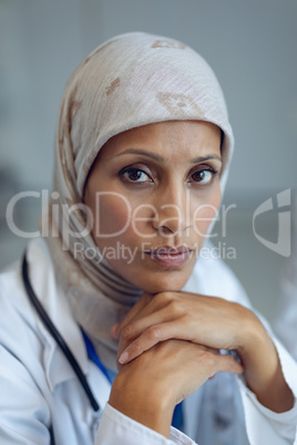 Female doctor sitting with head on hands in hospital