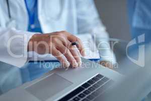 Male doctor sitting with laptop in hospital