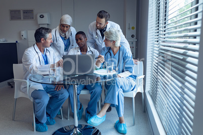 Medical team discussing over laptop on table at hospital