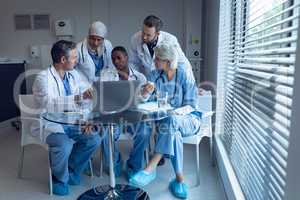 Medical team discussing over laptop on table at hospital