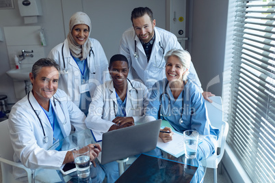 Happy medical team sitting on chair at hospital