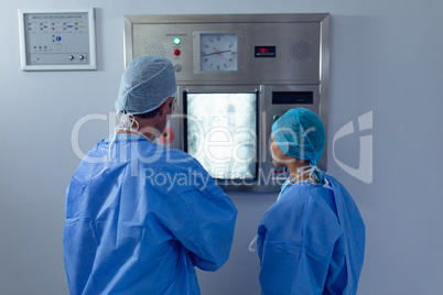 Surgeons examining x ray on x-ray light box at hospital