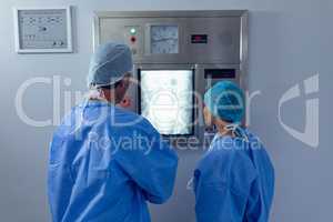 Surgeons examining x ray on x-ray light box at hospital