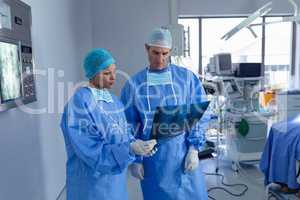 Surgeons discussing over x ray report in operating room at hospital