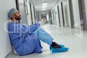 Tensed male surgeon sitting in the corridor