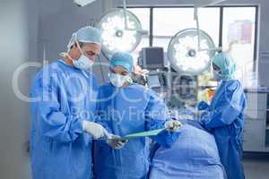 Surgeons discussing over medical file in operation room at hospital