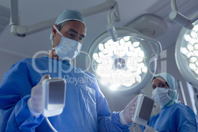 Male surgeon holding defibrillator in operation room at hospital