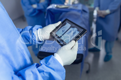 Surgeon looking x-ray report on digital tablet in operating room at hospital