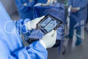 Surgeon looking x-ray report on digital tablet in operating room at hospital