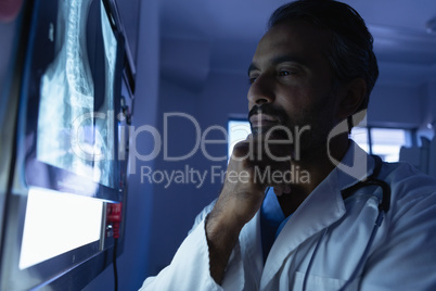 Mature male doctor looking at x-ray on x-ray light box in operation room at hospital