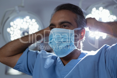 Mature male surgeon wearing surgical mask in operation room at hospital