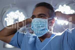 Mature male surgeon wearing surgical mask in operation room at hospital