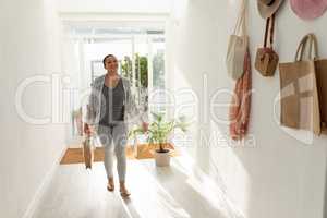 Young female entering her home with shopping bag