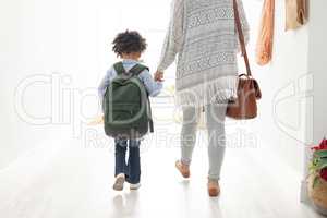 Girl with her mother walking together hand in hand near doorway at home