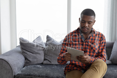 Man using digital tablet on sofa in living room