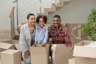 Family unpacking cardboard boxes in living room at home