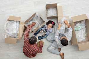 Family unpacking cardboard boxes in living room