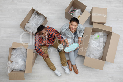 Couple unpacking cardboard boxes in living room at home