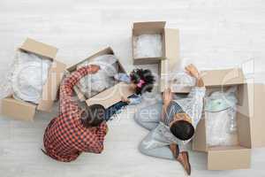 Family unpacking cardboard boxes in living room