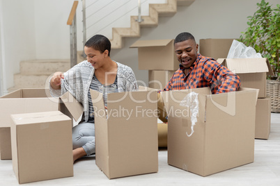 Couple unpacking cardboard boxes in living room