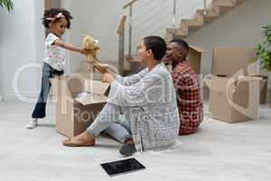 Girl giving teddy bear to mother in living room at home
