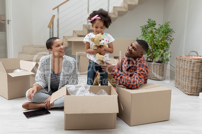 Family unpacking cardboard boxes in living room