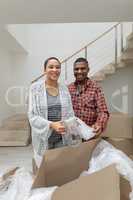 Couple unpacking cardboard boxes in living room at home