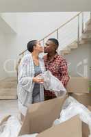 Couple kissing each other while unpacking cardboard boxes in living room
