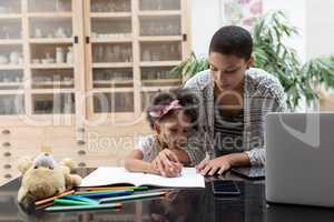Mother helping her daughter with her homework on a table