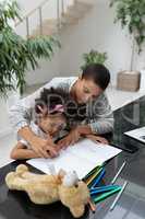 Mother helping her daughter with her homework on a table