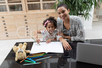 Mother helping her daughter with her homework on a table at home