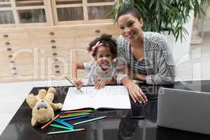 Mother helping her daughter with her homework on a table at home