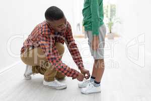 Father tying his sons shoelaces at home