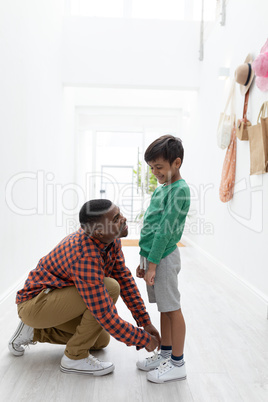 Father tying his sons shoelaces at home