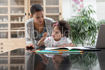 Mother helping her daughter with her homework on a table