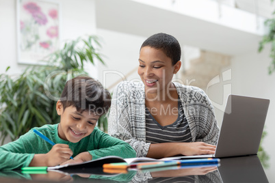 Mother helping his son with his homework on a table