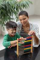 Mother teaching his son about abacus on a table