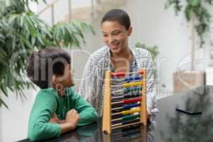 Mother teaching his son about abacus on a table