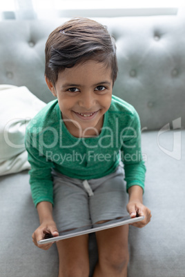 Boy using digital tablet on a sofa in living room at home