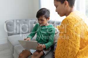 Mother and son using digital tablet on a sofa in living room