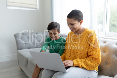 Mother and son using laptop on a sofa in living room