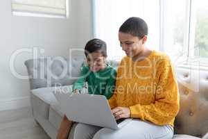 Mother and son using laptop on a sofa in living room