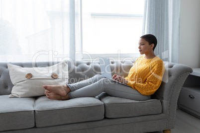 Woman using laptop on a sofa in living room