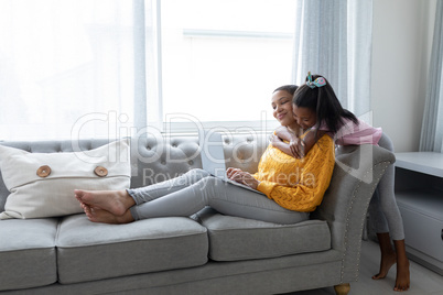 Mother and daughter embracing each other on a sofa in living room