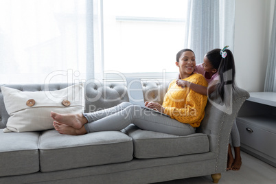 Mother and daughter embracing each other on a sofa in living room