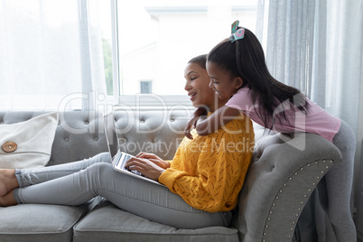 Mother and daughter embracing each other on a sofa in living room