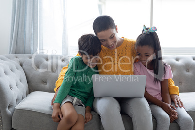 Mother and children using laptop on a sofa in living room