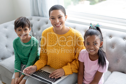 Mother and children using laptop on a sofa in living room at home