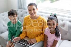 Mother and children using laptop on a sofa in living room at home